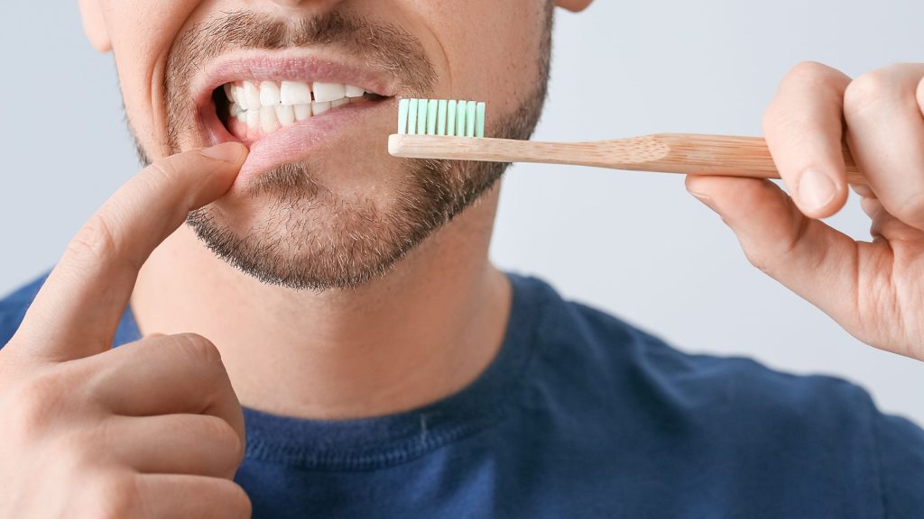 Man Holding A Toothbrush While Checking His Gums
